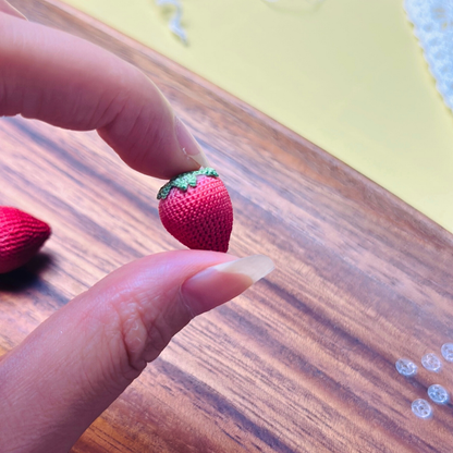 Single micro crochet strawberry held in hand, showing tiny berry size and structure