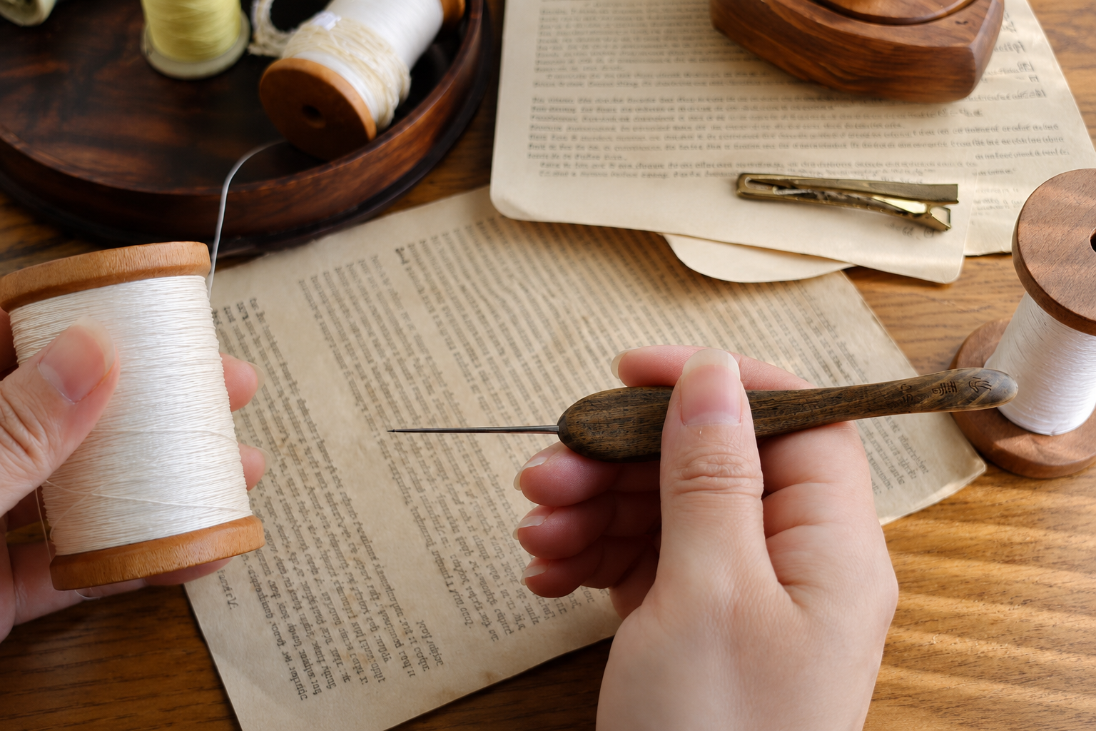 Hands holding a fine micro crochet hook and white thread during the making process