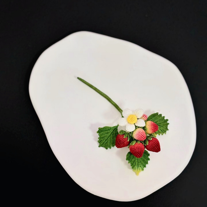 Close up of micro crochet strawberry, fine lace stitches and leaf texture