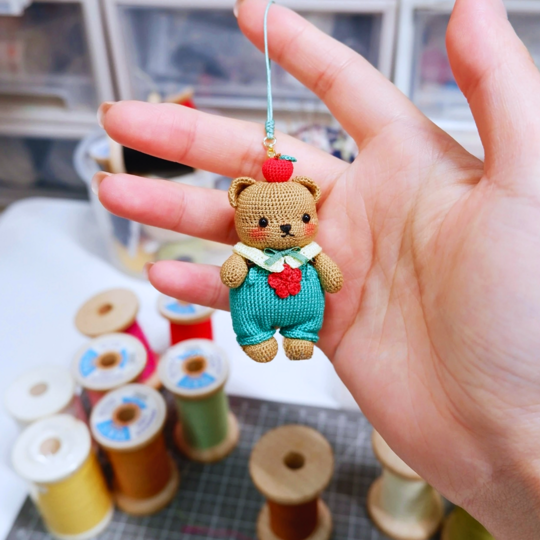 Brown micro crochet bear charm used as a pendant or bag charm – lightweight handmade accessory.
