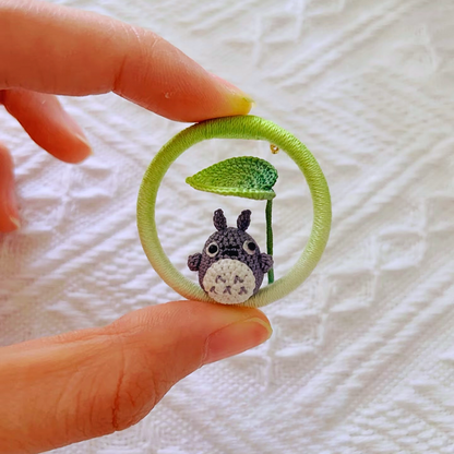 hand holding micro crochet Totoro inspired anime brooch with small green leaf
