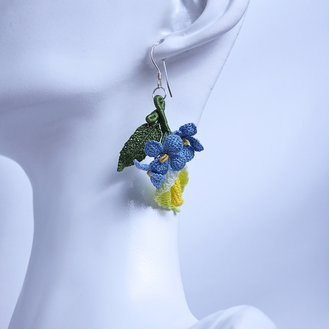 Close-up of micro crochet floral earrings with calla lily and blue flax, lightweight design