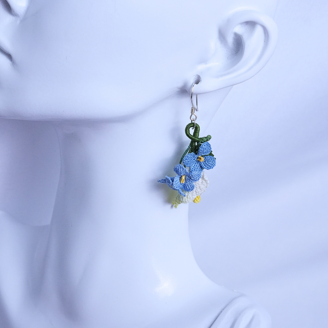 Micro crochet calla lily and blue flax earrings worn on ear, pastoral floral style