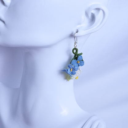 Micro crochet calla lily and blue flax earrings worn on ear, pastoral floral style
