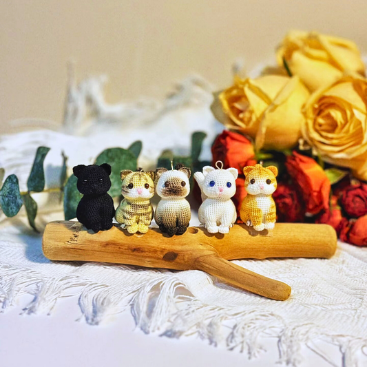 multiple micro crochet custom cat charms in different coat colours lined up on table, chubby squat cat design