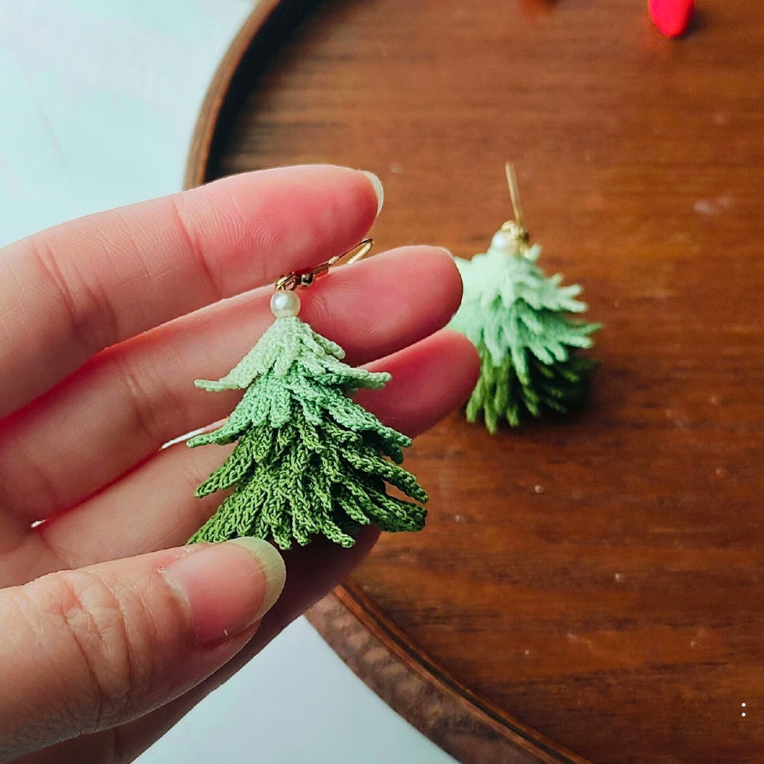 Micro crochet Christmas tree earrings held in hand to show size and lightweight design.