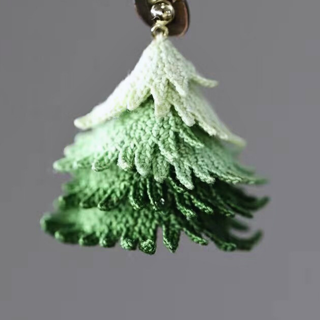 Close-up detail of handmade micro crochet Christmas tree earrings showing fine lace thread work.