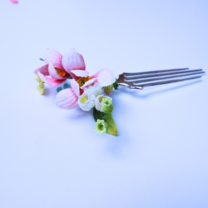 Soft flat lay of a micro crochet magnolia hair comb with pink flowers and delicate spring details