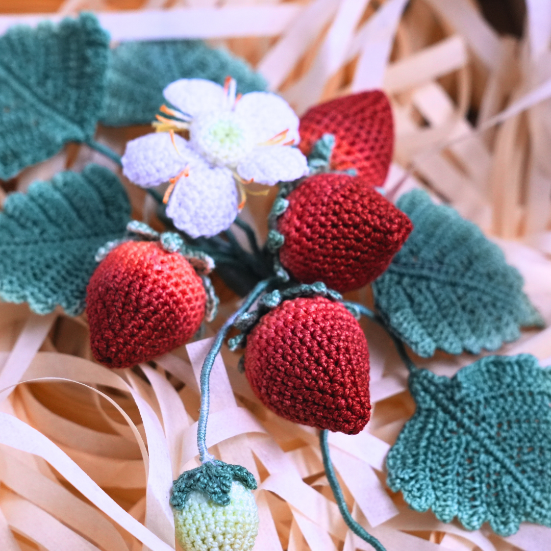 Close up detail of micro crochet strawberry earrings stitched seed by seed with fine lace thread