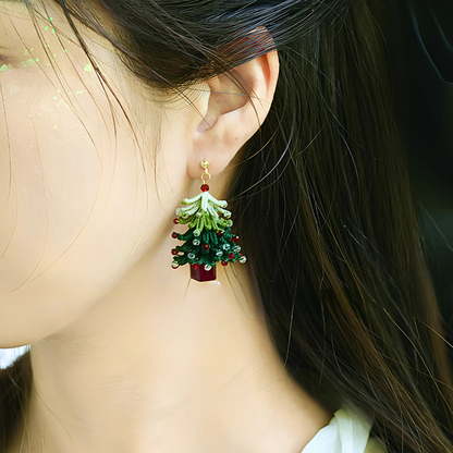 Short-style handmade micro crochet Christmas tree earring worn on the ear, showing its layered green branches and red and clear bead details.